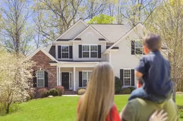 Mixed Race Young Family Looking At Beautiful New Home.