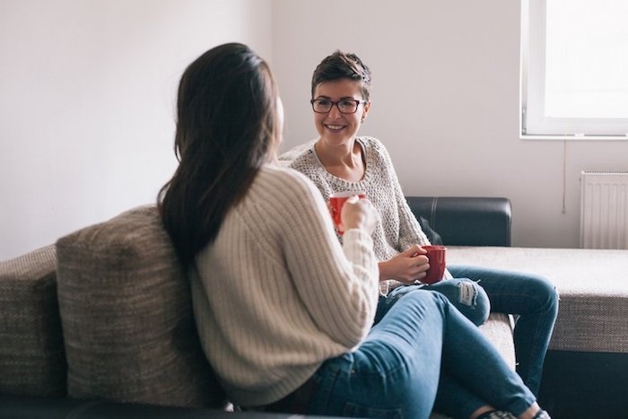 nanny relationship, women, friends, coffee, tea, mugs, blue, jeans, sweater, gray, brunette, glasses, smiling, happy